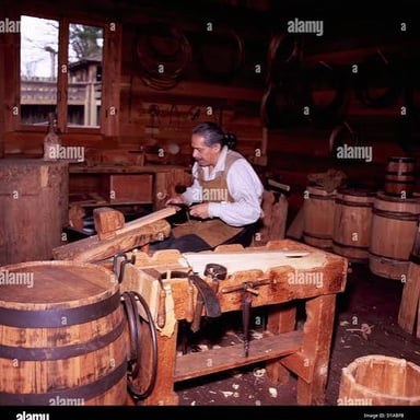 A craftsperson fitting wooden staves together to make a barrel.