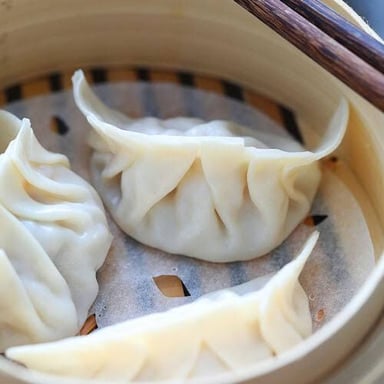 Steamed dumplings arranged in a bamboo steamer.
