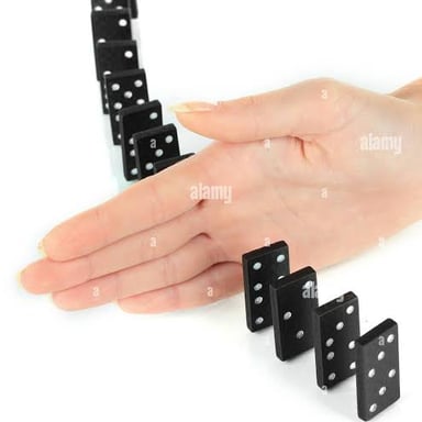 A hand stops a line of dominoes from falling.