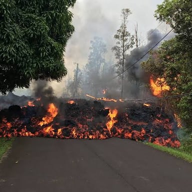 A glowing lava flow moving across volcanic ground in Hawaii.