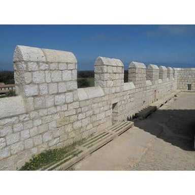 A raised stone defensive wall along the edge of a fort.