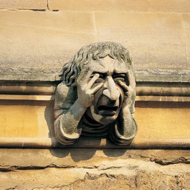 A stone gargoyle with an exaggerated, distorted face.
