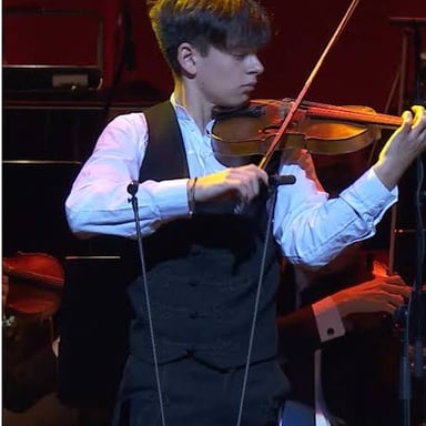 A violinist playing onstage with focused, practiced technique.