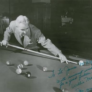 A skilled billiards player taking a shot in a pool hall.