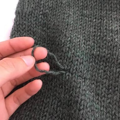 A pulled thread forming a small snag in knitted fabric.
