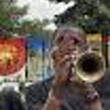 A musician blowing into a trumpet.