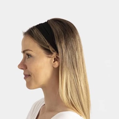A fabric headband holds a person's hair away from their face.