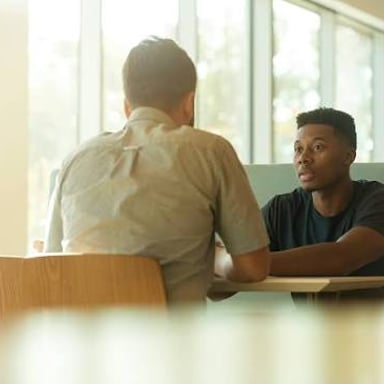Two people engaged in a direct, serious conversation.