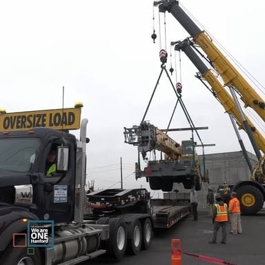 An industrial crane lifting a large, heavy cargo load.