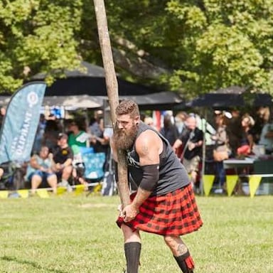 A competitor at a Highland Games event tosses a long wooden caber.