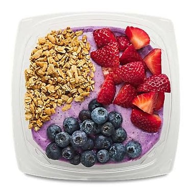 Dark-purple açaí fruit beside a chilled açaí bowl topped with granola and fruit.