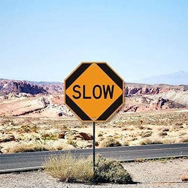 A roadside sign displaying SLOW, matching the first word of “slow eater.”