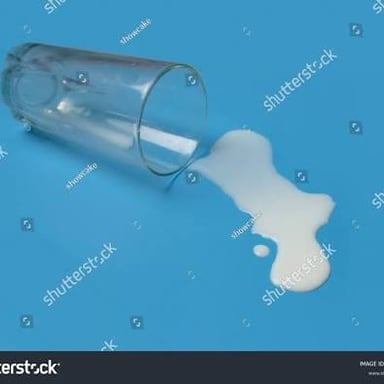 A small spill of milk beside a glass, suggesting an “oopsy” moment.