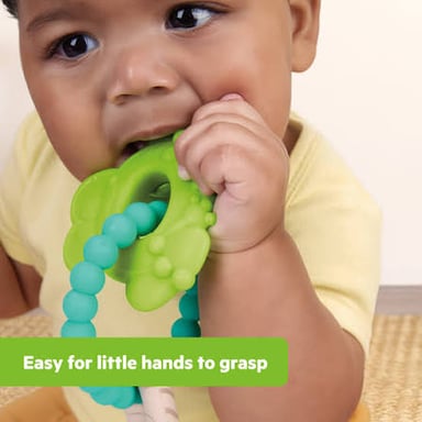 A baby holding a teething ring, illustrating the process of teeth coming in.