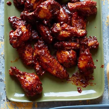 Chicken wings coated in a bright red, spicy sauce.