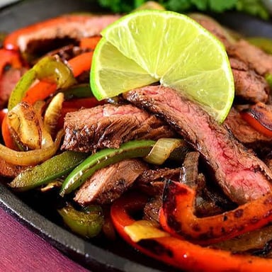 A sizzling fajita dish served in a hot skillet.