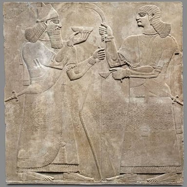 A shallow stone carving shows figures projecting from a flat panel.