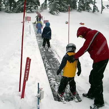 Skiers being pulled uphill by a T-bar lift.