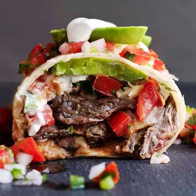 A burrito filled with sliced grilled beef, the carne asada preparation.
