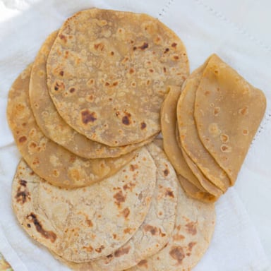 A bowl of atta flour beside freshly cooked roti.