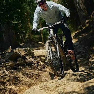 A cyclist rolling downhill with feet off the pedals, illustrating coasting.
