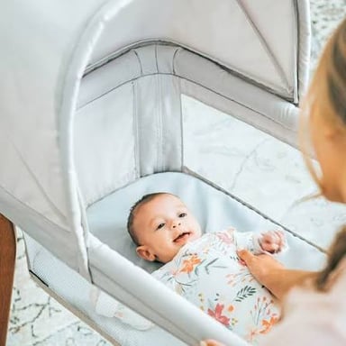 An infant resting in a small bassinet.