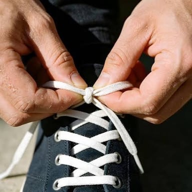 Hands pulling apart the knot in a sneaker's laces.