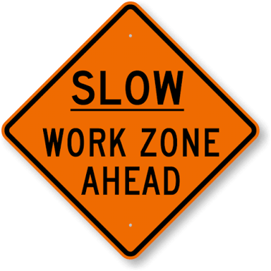 A SLOW road sign near a construction work area.