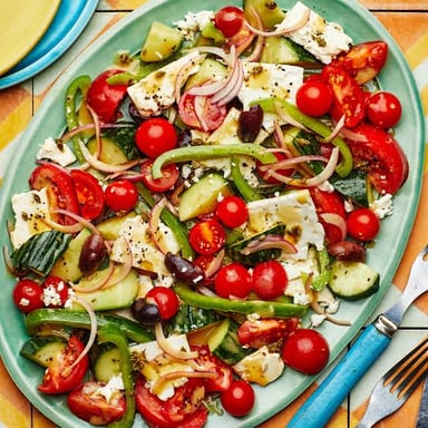 White feta cheese crumbled over tomatoes, cucumbers, olives, and greens