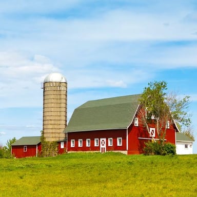 A tall farm grain silo standing beside a barn.