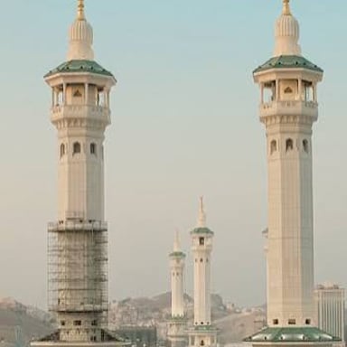 A minaret, a tower beside a mosque, rises above nearby buildings.