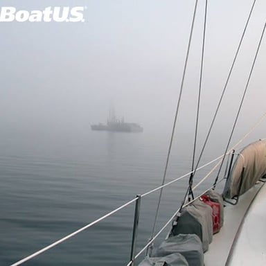 A boat on foggy water with visibility reduced around it.