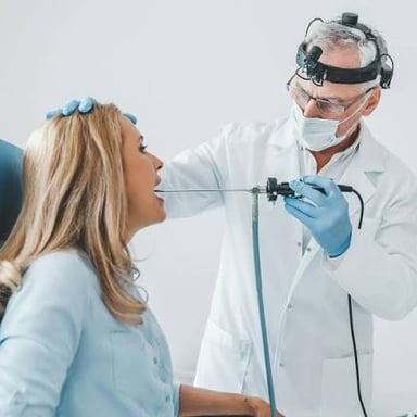 A clinician checks a patient’s throat during a routine appointment.