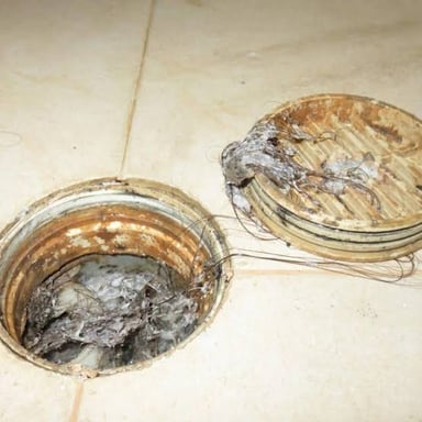 Debris blocking a drain and preventing water from flowing freely.