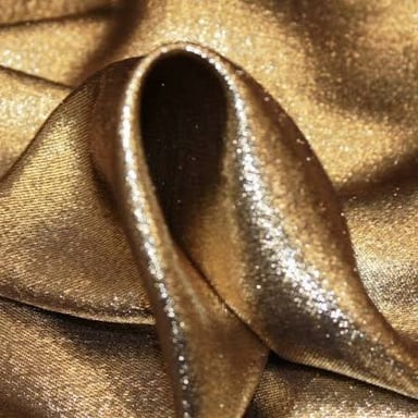 A close view of shimmering lamé fabric with metallic threads.
