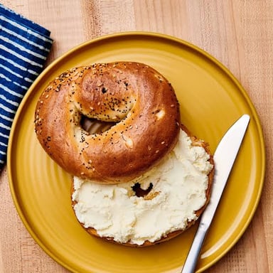 Cream cheese spread on a bagel, illustrating the dairy product in the wordplay.