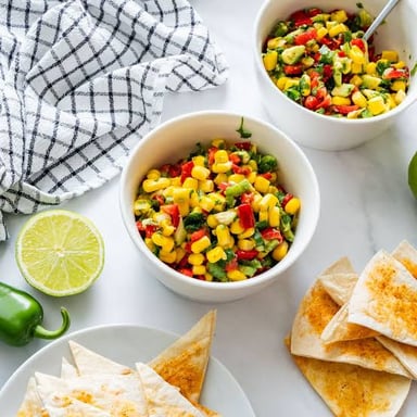 Corn salsa in a bowl, with kernels mixed among the other ingredients.