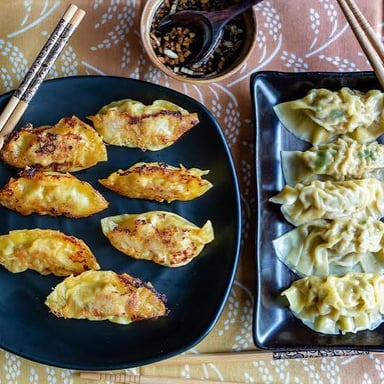 Chinese jiaozi dumplings with folded crescent-shaped wrappers, some boiled and some browned from pan-frying.