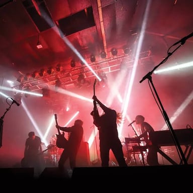 A metalcore band performing onstage with guitars and drums.