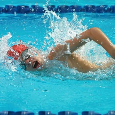 A swimmer moving through water with arm strokes and kicks.