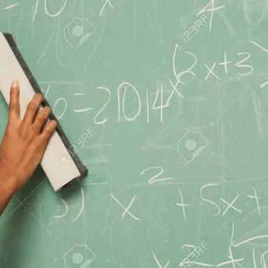 A hand erasing writing from a chalkboard