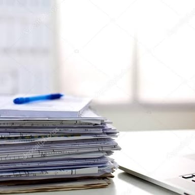 Loose documents and printouts stacked on a desk.