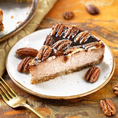 Pecan nuts beside a slice of pecan pie.