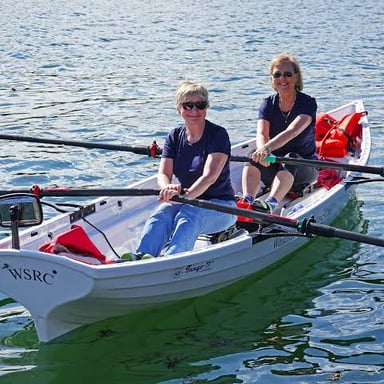 A person propelling a rowboat with two oars