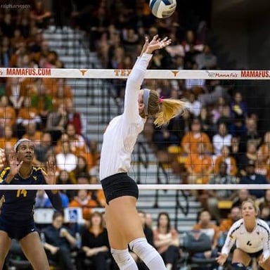 A volleyball player setting the ball upward for a teammate