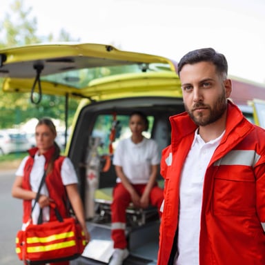 An emergency medical technician standing beside an ambulance.