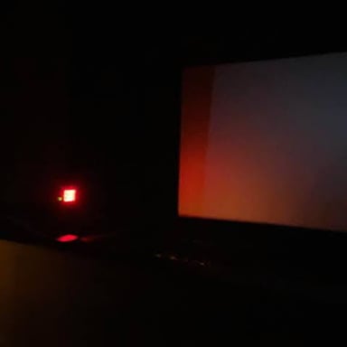 An illuminated EXIT sign above a theater door in a dim auditorium.