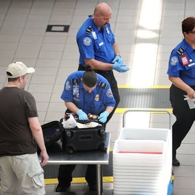Airport security officers inspect luggage at a checkpoint.