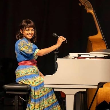 Norah Jones performing at a piano.