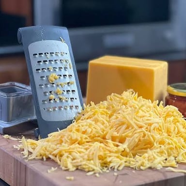 A wedge of Parmesan cheese with freshly grated cheese beside it.